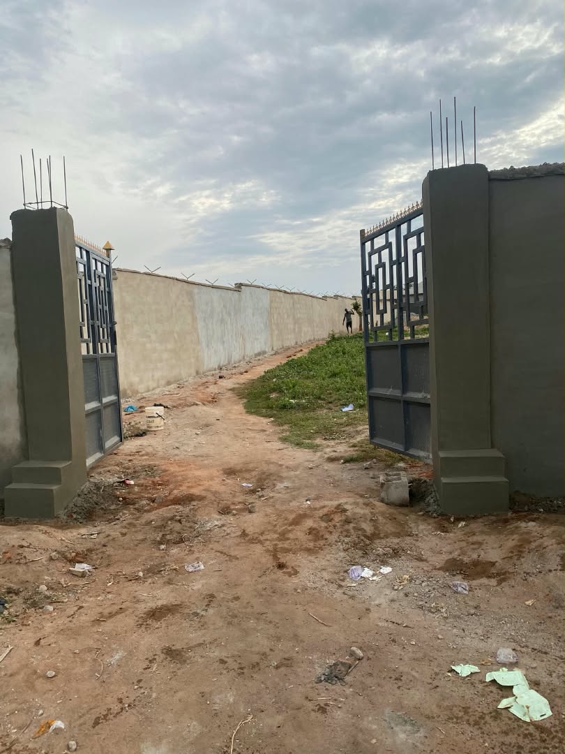 Company site photograph showing gate pillars under construction along a perimeter wall