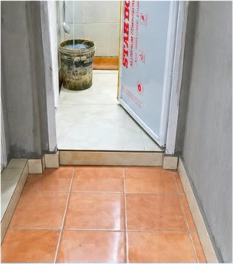 Company site photograph showing tiled corridor flooring leading to a bathroom during renovation works
