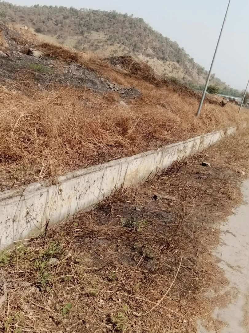 Supplied site photograph showing a concrete channel alongside a hillside with dry vegetation