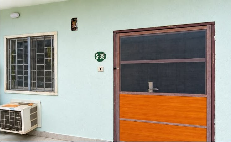 Company site photograph showing a completed exterior wall finish with window, security door and external unit