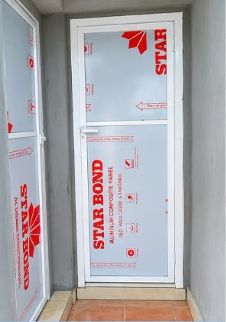 Company site photograph showing an internal door still wrapped in protective packaging during installation