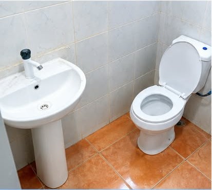 Company site photograph showing completed bathroom tiling with WC and wash basin fixtures installed